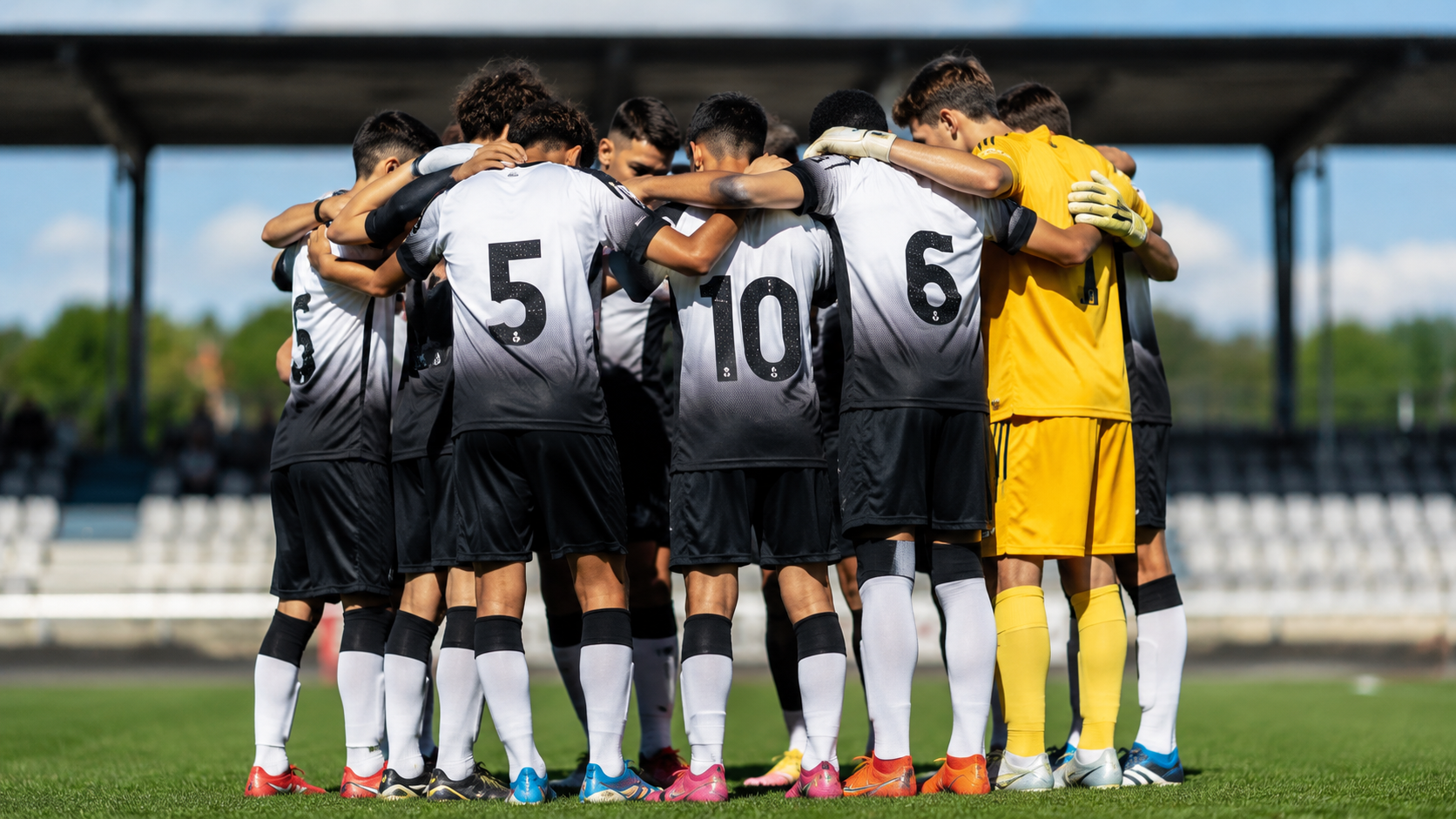 Time de futebol de base reunido em roda no gramado antes de uma partida, simbolizando a formação de jovens atletas no Brasil